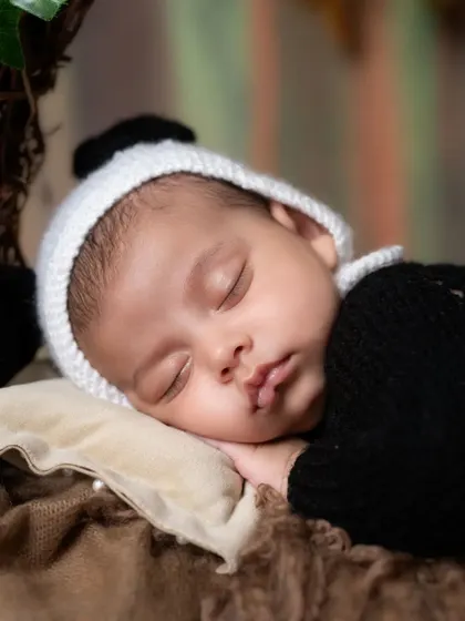 A close-up portrait of the sleeping baby in the panda outfit, showing the delicate features of his face.