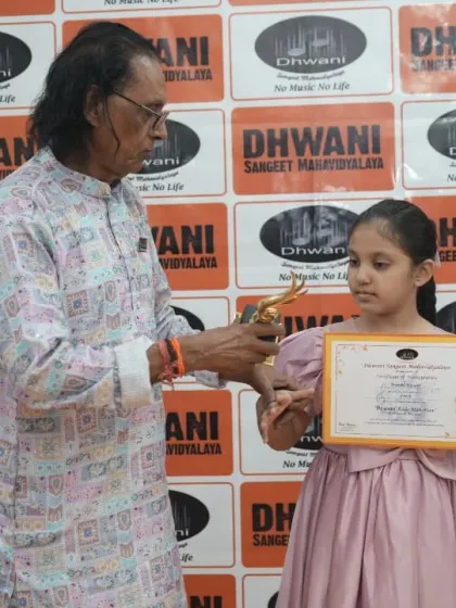 A senior guru presents an award to his young student.