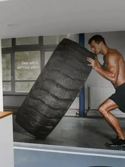 A custom wall mural of an athlete flipping a tire adds a raw, high-intensity feel to this fitness center. It’s a great way to define a functional training zone and motivate members during their workout.