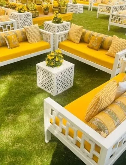 Modern white and yellow lounge seating on a green lawn, offering a chic and comfortable space for guests at a Haldi function.