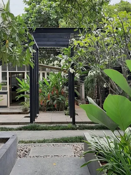 The entrance to a garden defined by a modern black pergola. This structure acts as a gateway, creating a sense of transition from the house into the lush outdoor space.