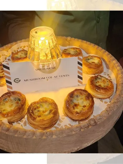 Creamy Mushroom Vol-au-vents served on a rustic wooden tray. The warm glow of the candle highlights the golden, flaky pastry of these delicious bites.
