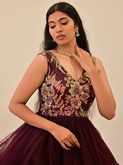 A close-up of a model in a deep purple gown. The makeup is soft and romantic, with a focus on rosy cheeks and a gentle shimmer on the eyes.
