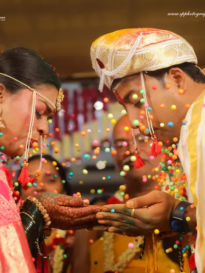 A close-up of the Akshata ritual, focusing on the couple's hands and the colorful grains. This shot highlights the beauty and detail of the wedding traditions.