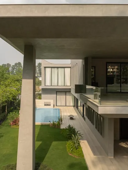Views of the home from the garden, showing how the monumental concrete forms are softened by the surrounding greenery. The design creates a constant interplay between the architecture and the landscape.