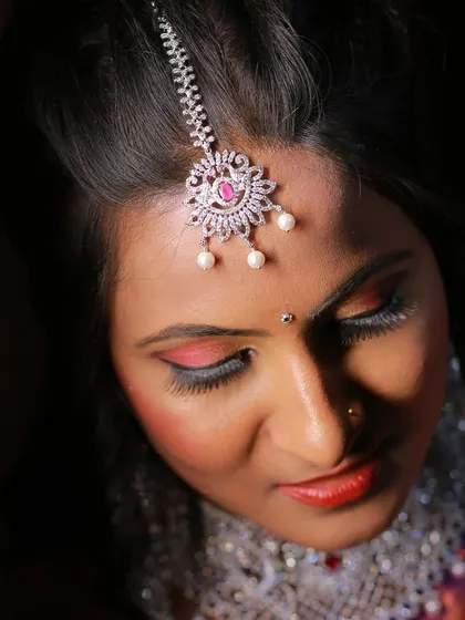 A detailed top-down shot of a bride, focusing on her eye makeup and maang tikka.