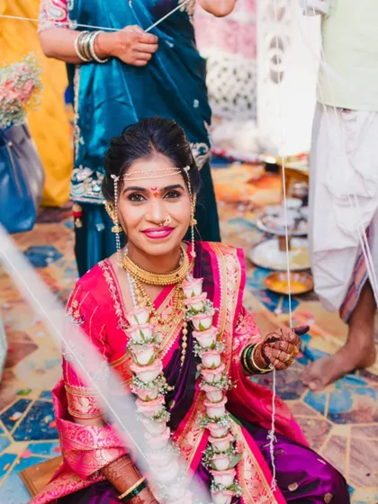 A beautiful candid shot of the bride during her wedding ceremony, smiling as she participates in the traditional rituals.