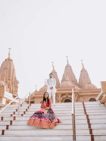 A wide, symmetrical shot of the couple on the temple steps, emphasizing the grandeur of the location.