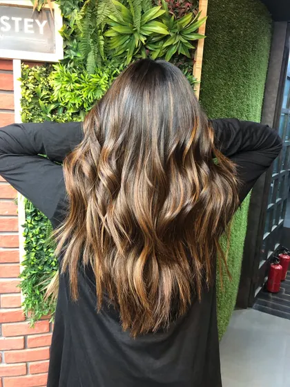 A perfect example of a caramelized balayage with a face-contouring money piece. This technique gives a more natural, blended result than traditional highlights.