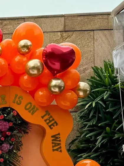 A close-up of the balloon artistry from the "Little Cutie" baby shower, showing a mix of orange, red, and gold balloons.