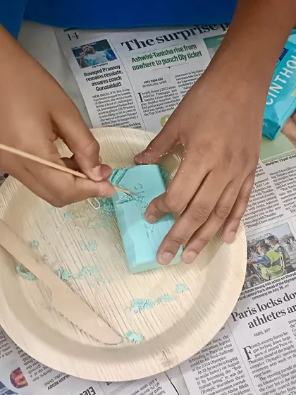 A child's hands are seen carefully carving a design into a bar of soap, a wonderful fine motor activity that connects art with cultural history.