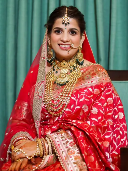 A beautiful, classic bridal portrait. The bride's radiant smile and her elaborate, traditional jewelry are the stars of this photo.
