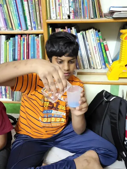 A young chemist in action, carefully pouring liquid from one container to another during an experiment.