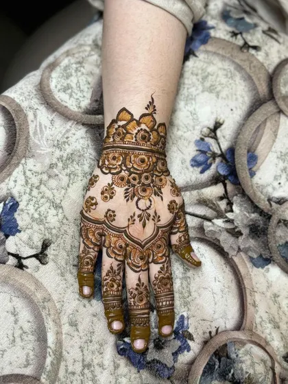 A close-up of one hand, highlighting the floral cuff and finger details.