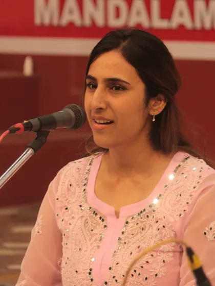 A student presenting a devotional song with a gentle smile, enjoying the act of singing.