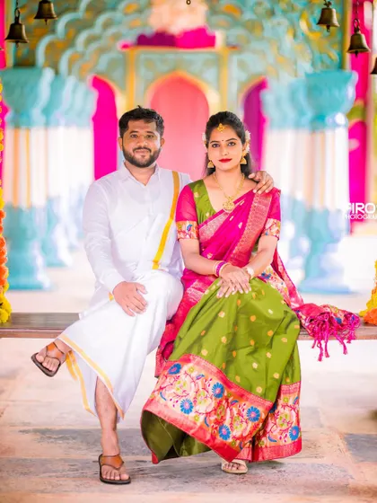 A vibrant and colorful portrait of a couple on a swing decorated with marigolds. Their traditional attire pops against the lively, festive background.