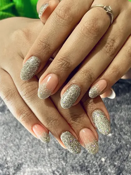 Can we talk about these nails? This stunning design features a reverse French manicure with a full-coverage silver glitter.