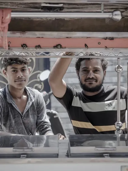 Capturing the interaction between vendors and their environment. This shot frames two men in their food stall, offering a glimpse into their daily work life.