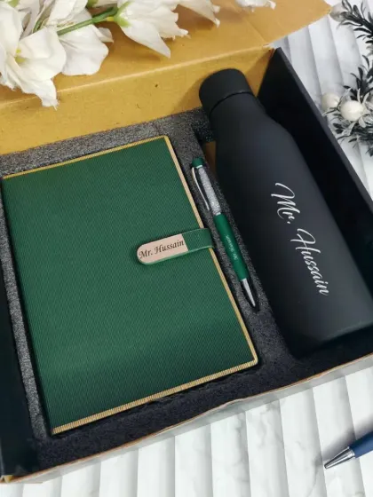 A sophisticated green and black personalized gift set for "Mr. Hussain". The set includes a green faux-leather diary with a custom name clasp, a matching pen, and a matte black temperature bottle.