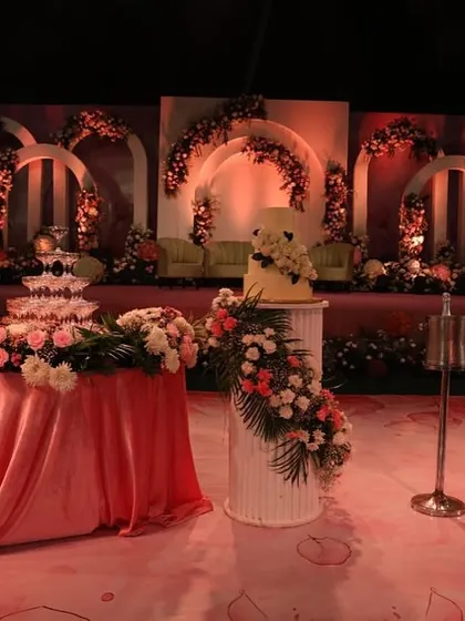 The cake cutting is a key moment, and we ensure the setting is just as sweet. Here, the wedding cake and champagne tower are positioned as a beautiful focal point against the floral stage backdrop.