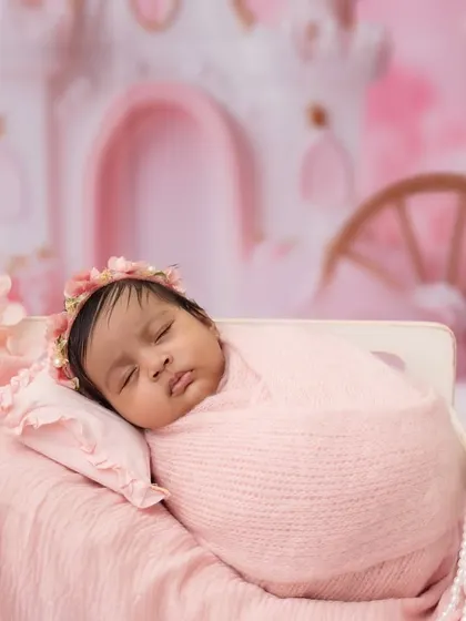 This angle highlights the delicate pearl details on the miniature bed, coordinating perfectly with the baby's pink wrap and floral headband.