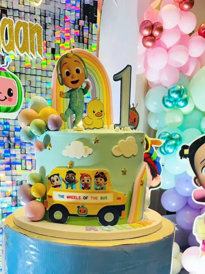 A client photo of the Cocomelon cake at the party. It fits perfectly with the colorful decorations and the big light-up number one.