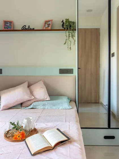 A detail shot of this bedroom, where a floating shelf above the headboard provides a space for personal touches without adding clutter.