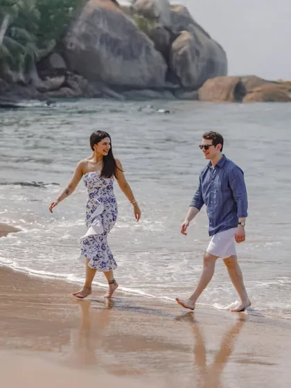 A relaxed and happy pre-wedding photo of a couple walking along the shores of a Goa beach.