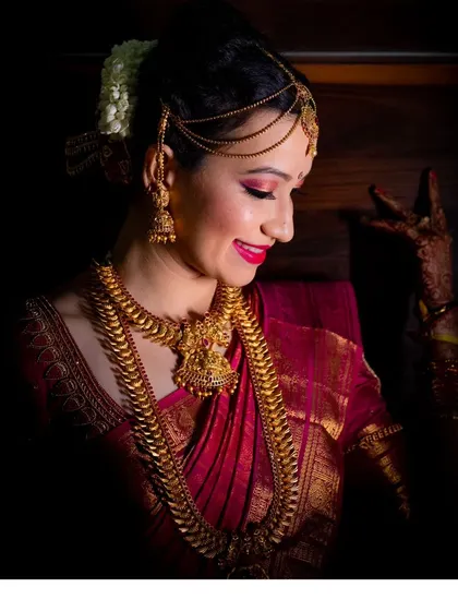 A stunning low-light portrait of a bride, showcasing her beautiful traditional jewelry and makeup.