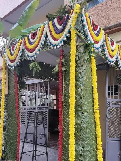 A simple yet beautiful chapra for a home entrance. It's constructed with woven palm leaves and adorned with colorful flower garlands and banana leaves.