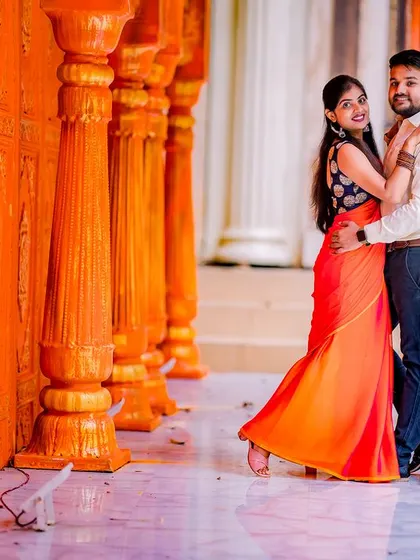 A candid and happy moment in a vibrant orange corridor. The couple's natural interaction and the bright colors create a joyful and energetic pre-wedding photo.