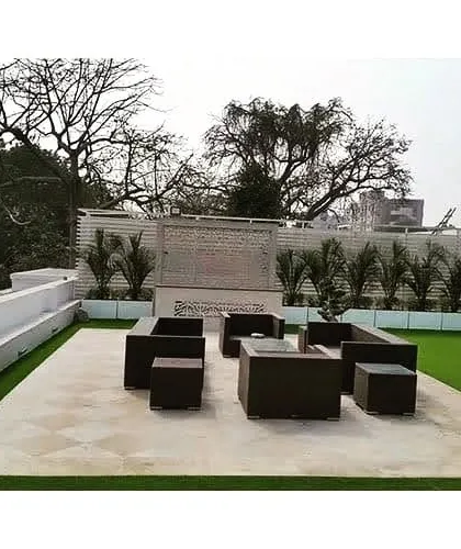 We designed this spacious terrace as an outdoor lounge. The area features a large seating arrangement on a paved section, surrounded by a pristine artificial lawn and a feature bonsai tree.