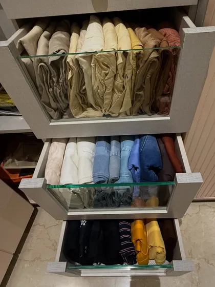 Three drawers pulled open to showcase how we organize different types of trousers. From light-colored linens to dark denim, each category is grouped and folded for maximum visibility and space efficiency.