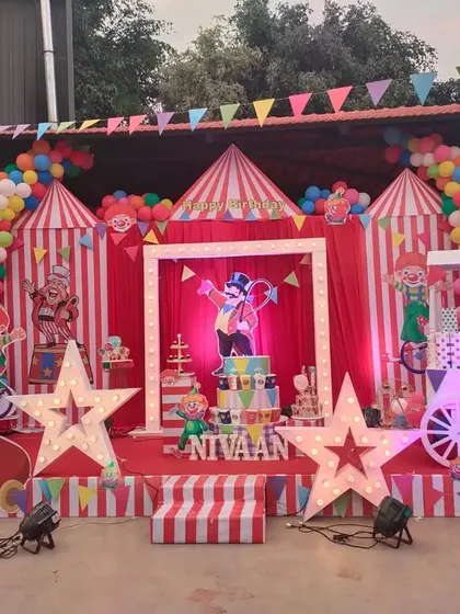 Step right up to a spectacular carnival-themed 5th birthday party. This grand outdoor setup features a classic red and white striped circus tent backdrop, light-up star props, a ticket booth-style cart, and fun clown cutouts to bring the big top to life.
