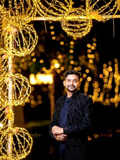 A handsome groom portrait at an evening reception, framed by an arch of glowing orb lights.