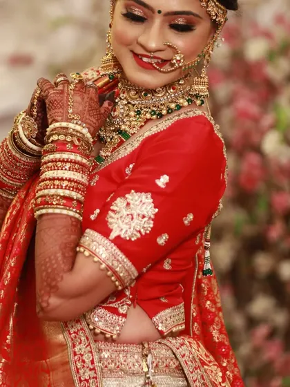 A graceful pose by a bride, showcasing her full bridal look. The mehndi on her arms and hands ties the whole look together beautifully.