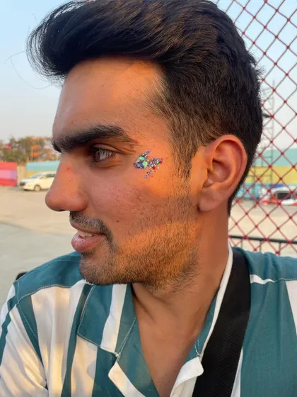 A multi-colored glitter design on a male client. The mix of blue, green, and purple creates a cool, galaxy-like effect.