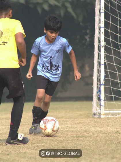 A young athlete in our signature blue jersey dribbles with determination. Our league provides the perfect stage for kids to express themselves and grow their confidence with the ball at their feet.