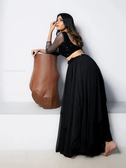 A minimalist fashion portrait in an all-black outfit. The simple white background and a unique prop create a modern, artistic composition.