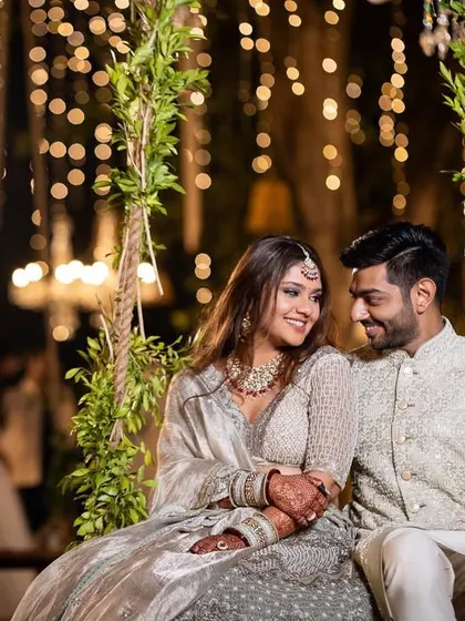 A romantic moment on a floral swing, with the couple framed by lush greenery and a beautiful bokeh of fairy lights in the background.