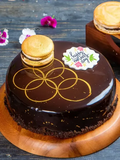 An elegant Dark Chocolate Fantasy cake, decorated with a golden macaron and a beautiful hand-drawn pattern. This premium cake is perfect for special occasions like Mother's Day.