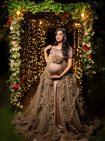 A full-length view of the mom-to-be in a beautiful gown, framed by an arch of lights. This shot has a wonderful, celebratory feel.
