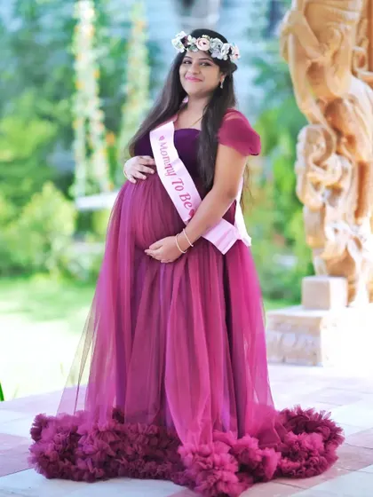 A fun and celebratory outdoor portrait featuring a "Mommy to Be" sash and floral crown. Props like these can add a personal and festive touch to your baby shower or maternity shoot.