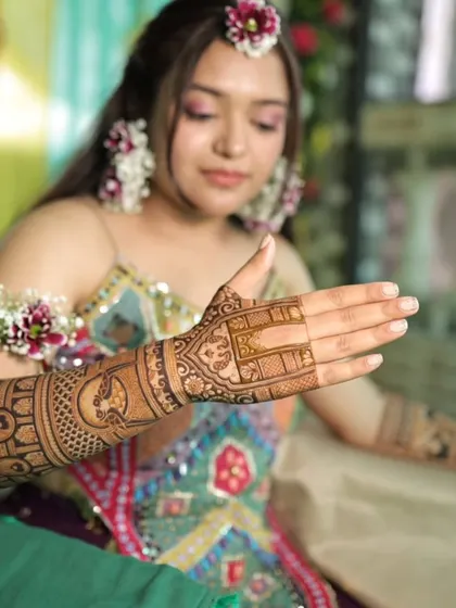 A bride showing her elegant back-hand mehandi. The design is a perfect complement to her floral jewelry.