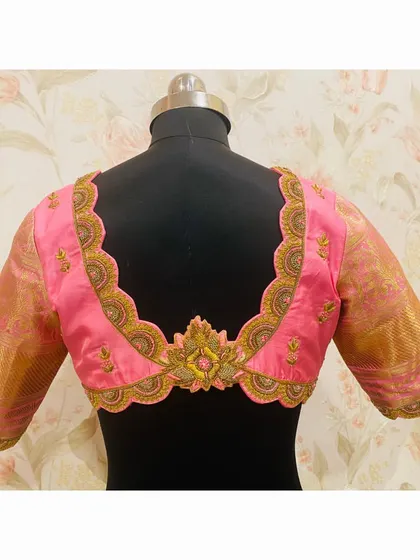 The back of the scalloped pink blouse, featuring a beautiful cutwork design and a central embroidered motif.