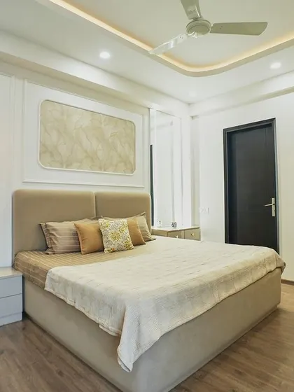 A wider angle of the bedroom, showing the ample space and the clean, modern design of the furniture and ceiling.