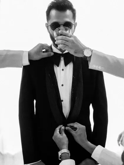 A stylish black and white shot of the groom getting ready, with a little help from his friends. This editorial-style photo is cool, candid, and full of character.
