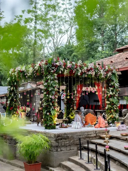 A view of the floral mandap from across the Kalyani, showing how the decor harmonizes with the venue's natural and architectural beauty. The reflection in the water adds another layer of magic to this wedding setup.