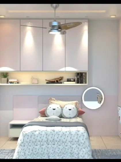 A charming kids' room with a pink and white theme, featuring a bed with cute lion-faced cushions and overhead storage cabinets.