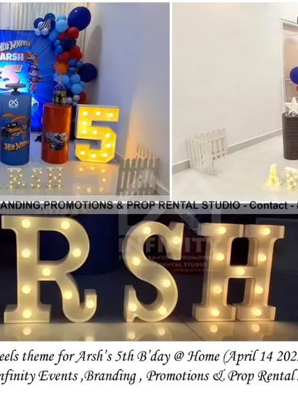 A supercharged Hot Wheels theme for a 5th birthday at home. This setup includes a dynamic backdrop, a blue and red balloon garland, themed cylinder props, and a large light-up number "5" for a fast and fabulous party.
